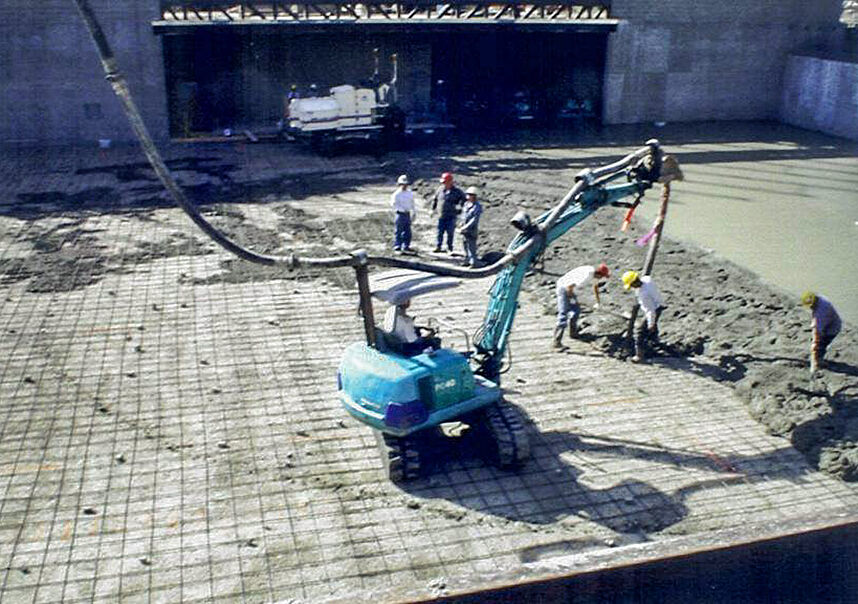Pump truck with excavator assistance pouring new concrete slab